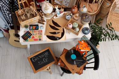 Photo of Sign Garage Sale written on blackboard near many different stuff indoors, above view
