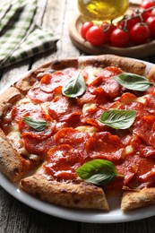 Photo of Tasty pepperoni pizza with basil on wooden table