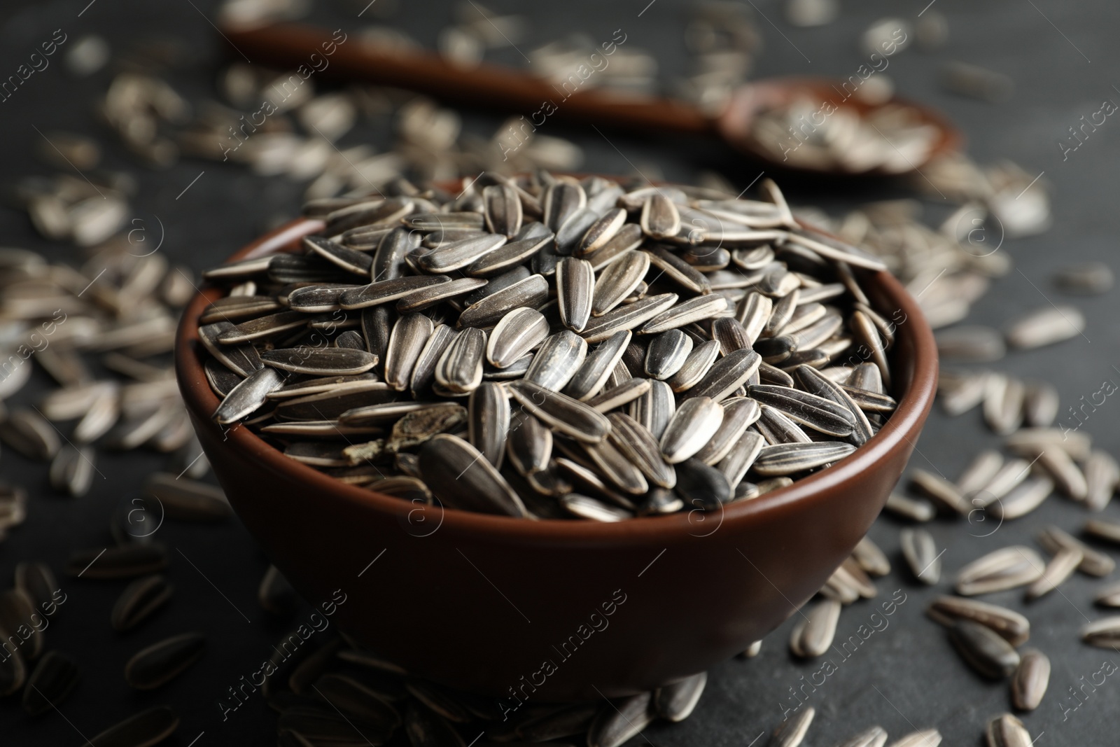 Photo of Organic sunflower seeds in bowl on grey table, closeup