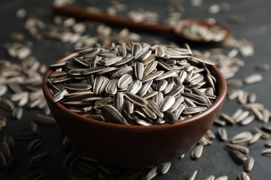 Photo of Organic sunflower seeds in bowl on grey table, closeup