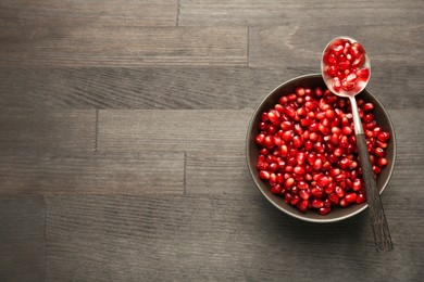 Photo of Tasty ripe pomegranate grains on dark wooden table, top view. Space for text