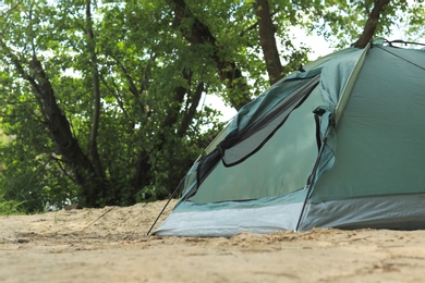 Photo of Modern camping tent near trees in wilderness