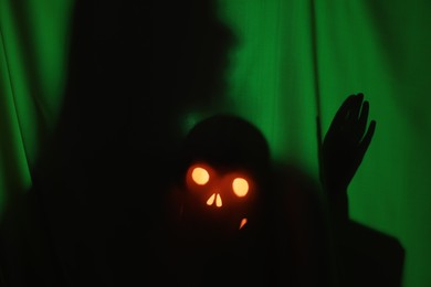 Photo of Silhouette of creepy ghost with skull behind dark green cloth
