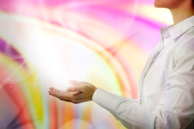 Image of Aura phenomena. Woman with flows of energy coming out from her hands against color background, closeup