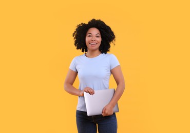 Photo of Happy young woman with laptop on yellow background