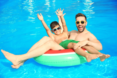 Photo of Father and son having fun in swimming pool. Family vacation