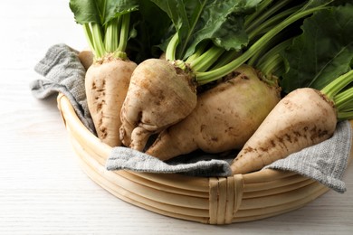 Photo of Basket with fresh sugar beets on white wooden table, closeup