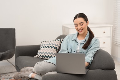 Photo of Woman using laptop on couch at home