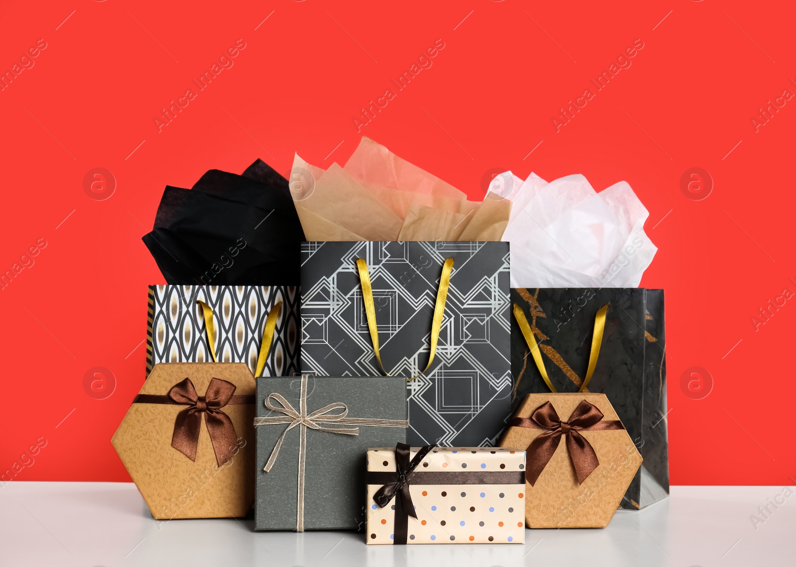 Photo of Shopping paper bags and gift boxes on red background