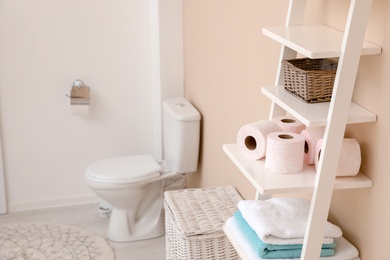 Photo of Toilet paper rolls on shelving unit in bathroom. Space for text