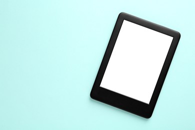 Photo of Modern e-book reader with blank screen on light blue background, top view. Space for text