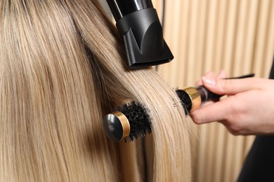 Photo of Hairdresser blow drying client's hair in salon, closeup