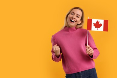 Image of Happy young woman with flag of Canada on yellow background