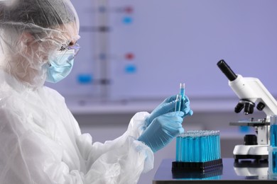 Photo of Scientist working with test tubes of light blue liquid in laboratory