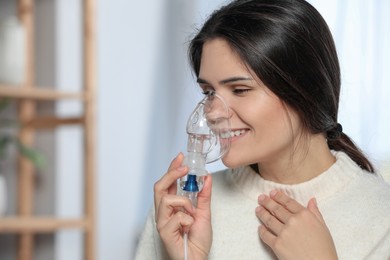 Photo of Sick young woman using nebulizer at home, space for text