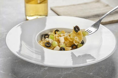 Photo of Tasty pasta salad with black olives and cheese on table