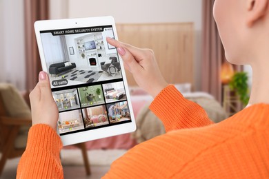 Image of Woman using smart home security system on tablet computer indoors, closeup. Device showing different rooms through cameras