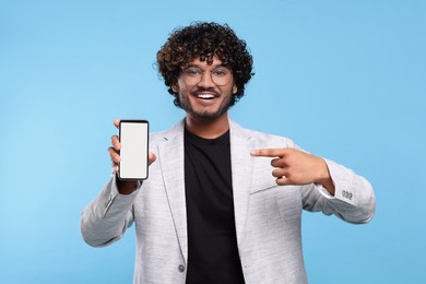 Photo of Handsome smiling man showing smartphone on light blue background