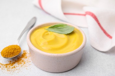 Photo of Tasty curry sauce, powder and basil leaf on light table, closeup