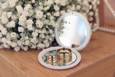 Photo of Pocket mirror, engagement rings and beautiful bouquet on wooden table. Wedding day