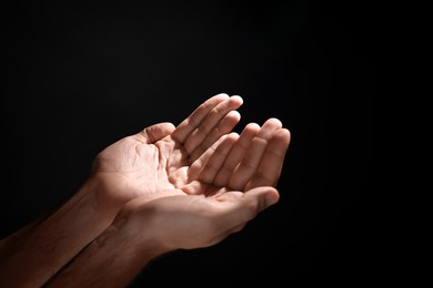 Photo of Man reaching hands to light in darkness, closeup