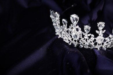 Photo of Beautiful silver tiara with diamonds on dark cloth. Space for text