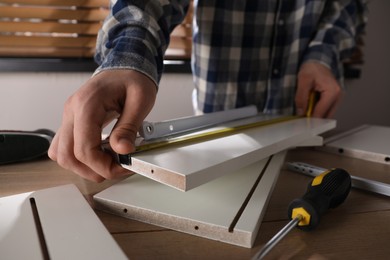 Photo of Man assembling furniture at table indoors, closeup
