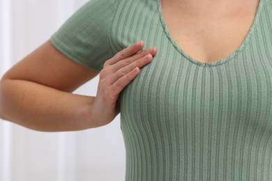 Photo of Mammology. Woman doing breast self-examination indoors, closeup