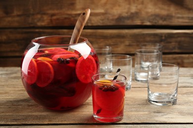 Photo of Bowl of delicious aromatic punch drink and glasses on wooden table