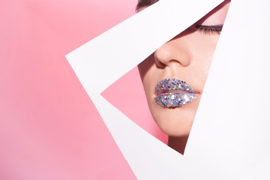 Photo of View of beautiful young woman with creative lips makeup through cutout in color paper