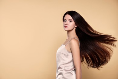 Photo of Portrait of beautiful young woman with healthy strong hair on beige background, space for text