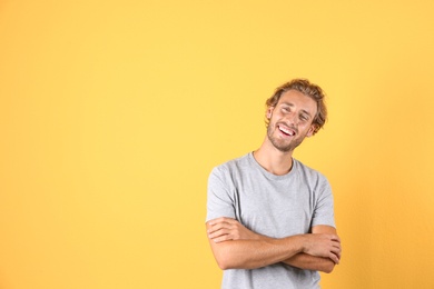 Photo of Handsome young man laughing on color background. Space for text