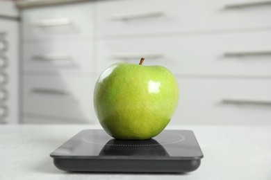 Green apple and modern digital scale on table