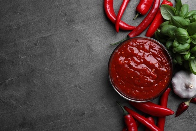 Photo of Flat lay composition with bowl of chili sauce and ingredients on grey table. Space for text