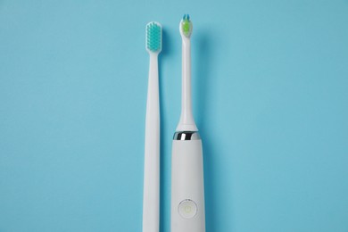 Photo of Electric and plastic toothbrushes on turquoise background, flat lay