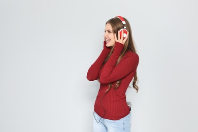 Photo of Young woman listening to Christmas music on color background