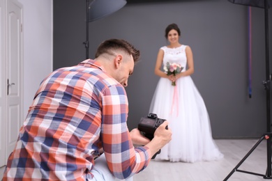 Photo of Professional photographer with camera and beautiful bride in studio