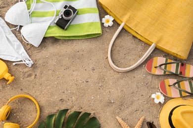 Photo of Frame made with beach accessories on sand, top view. Space for text