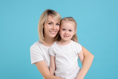 Photo of Family portrait of happy mother and daughter on light blue background