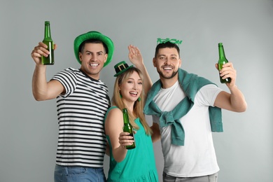 Photo of Happy people in St Patrick's Day outfits with beer on light grey background