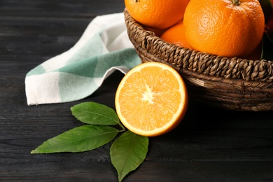 Photo of Delicious ripe oranges on black wooden table, closeup