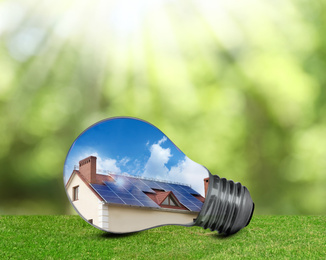 Image of Alternative energy source. Light bulb with solar panels outdoors