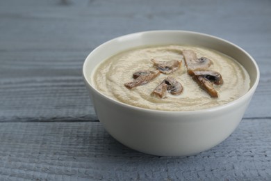 Photo of Delicious mushroom cream soup on light grey wooden table. Space for text