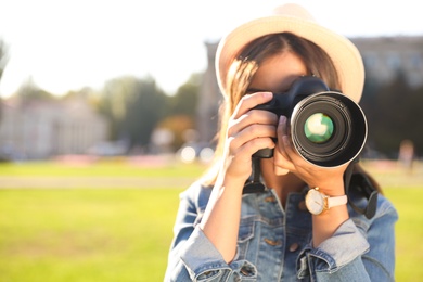 Photo of Young female photographer taking photo with professional camera on street. Space for text