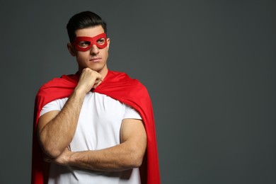 Photo of Man wearing superhero cape and mask on grey background. Space for text