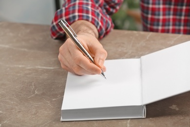 Photo of Writer signing autograph in book at table, closeup
