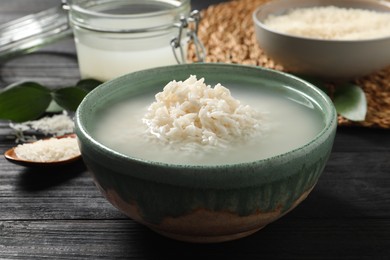 Photo of Bowl with rice soaked in water on wooden table