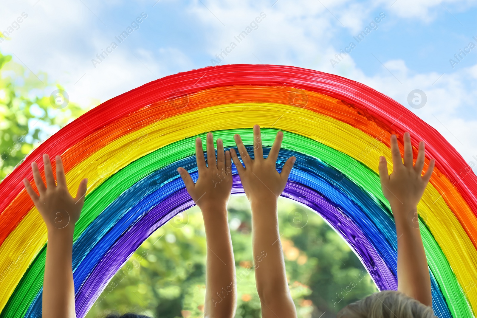 Photo of Children touching picture of rainbow on window, closeup. Stay at home concept