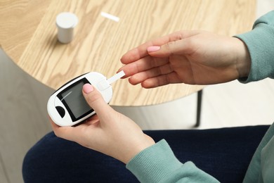 Diabetes. Woman checking blood sugar level with glucometer at home, top view