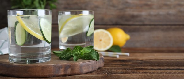 Image of Refreshing water with cucumber, lemon and mint on wooden table, space for text. Banner design